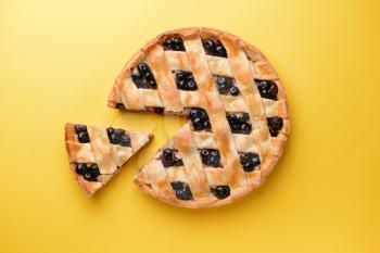 Tasty blueberry pie on color background�
