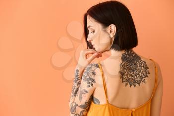 Beautiful tattooed woman on color background�