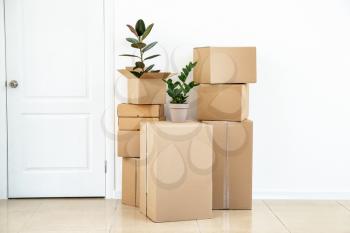 Cardboard boxes with belongings prepared for moving into new house near white wall�