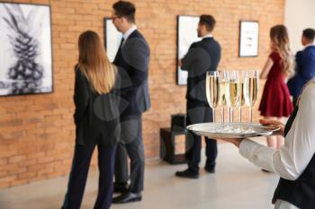 Waiter with champagne at exhibition in modern art gallery�
