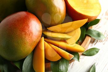 Board with tasty fresh mango on wooden table, closeup�