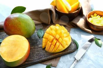 Cutting board with tasty sweet mango on table�