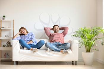 Happy young couple resting together on sofa at home�