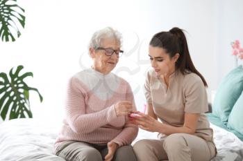 Caregiver giving medicine to senior woman in nursing home�