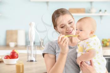 Mother feeding her little baby in kitchen at home�