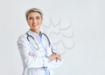Mature female doctor on light background�