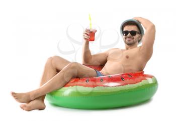 Happy young man with inflatable ring and cocktail on white background�