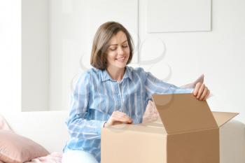 Young woman opening parcel at home�