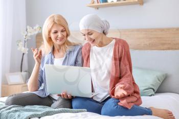 Woman after chemotherapy and her mother with laptop at home�