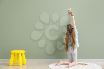 Cute little girl painting on wall in room�