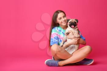 Teenage girl with cute pug dog on color background�