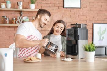 Young couple using coffee machine in kitchen�