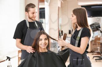 Hairdressers working with client in salon�