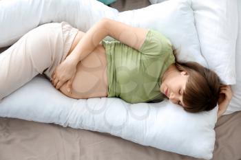 Young pregnant woman sleeping on maternity pillow at home�