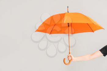 Female hand with umbrella on light background�