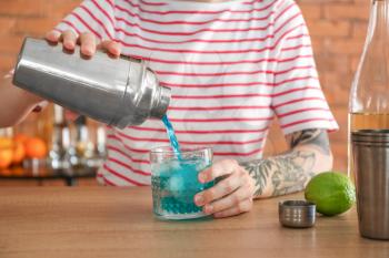 Woman preparing Blue Lagoon cocktail at table at home�