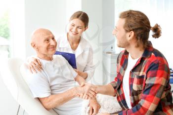 Young man visiting his elderly father in modern clinic�