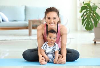 African-American mother training with cute little baby at home�
