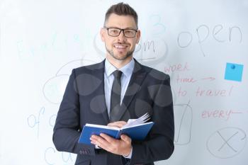 Handsome male teacher near blackboard in classroom�