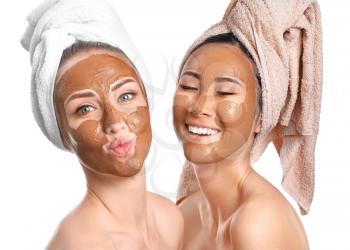 Beautiful women with facial masks on white background�