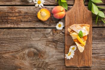 Composition with tasty peach pie on wooden background�