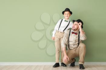 Portrait of fashionable father and son near color wall�