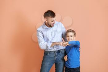 Father and his little son bumping fists against color background�