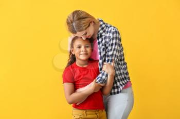 Happy woman with little adopted African-American girl on color background�