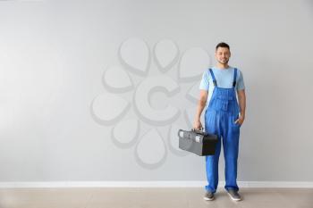 Portrait of handsome plumber with tools box near white wall�