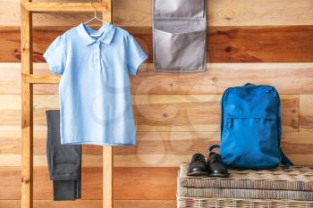 Stylish school uniform, backpack and shoes in room�