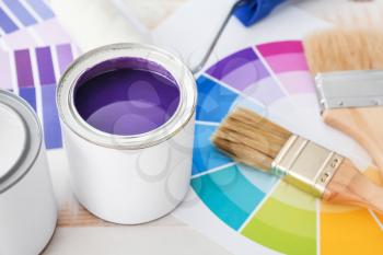 Cans of paint with brushes and palette samples on light background�