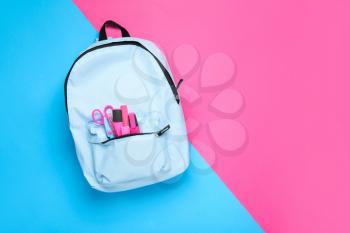 School backpack with stationery on color background�