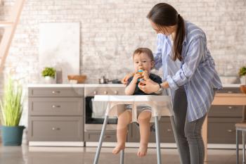Mother and her little son with nibbler in kitchen at home�
