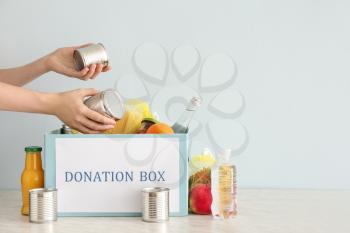 Volunteer putting food into donation box on table�