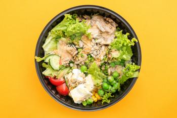 Container with delicious food on color background�