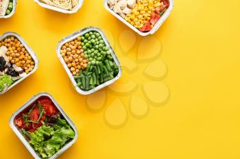 Many containers with delicious food on color background�