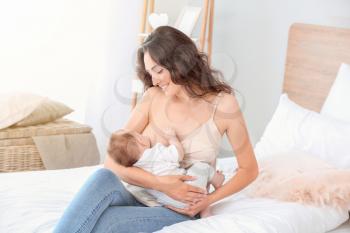 Young woman breastfeeding her baby at home�