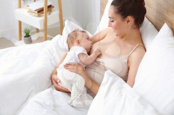 Young woman breastfeeding her baby at home�