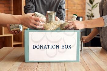 Volunteers putting donation food into box at table�