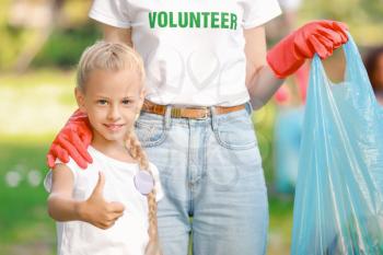 Little volunteer with woman gathering garbage in park�