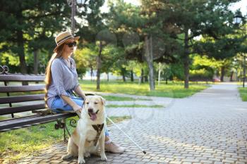 Young blind woman with guide dog in park�