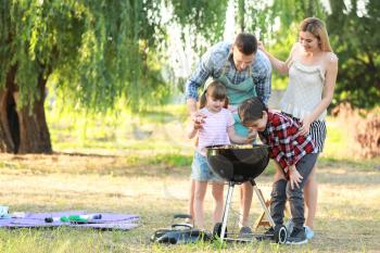 Happy family cooking tasty food on barbecue grill outdoors�