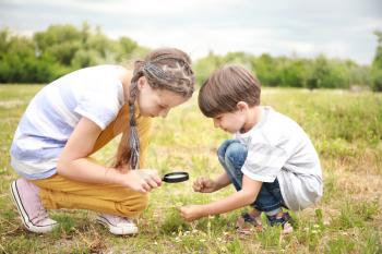 Little children with magnifying glass studying nature outdoors�