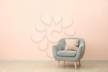 Comfortable armchair near color wall�