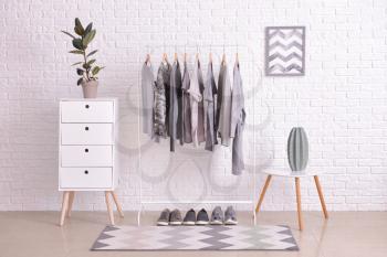 Rack with hanging clothes in interior of dressing room�