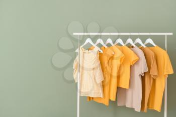 Rack with hanging clothes on color background�