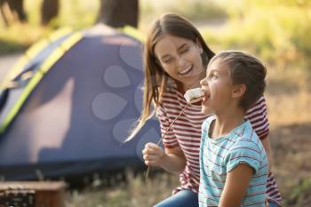 Mother and her little son roasting marshmallow on fire in forest�