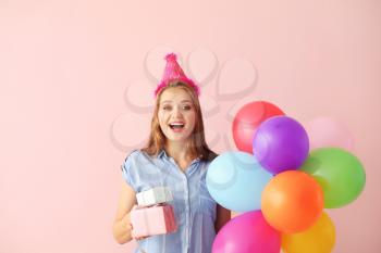 Happy woman with gifts and Birthday balloons on color background�