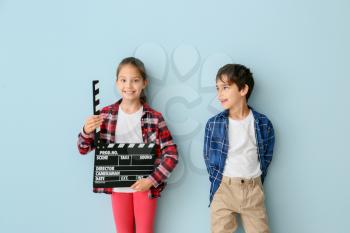 Cute little children with movie clapper on color background�