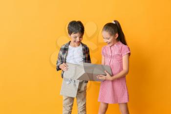 Cute little children opening gift box on color background�